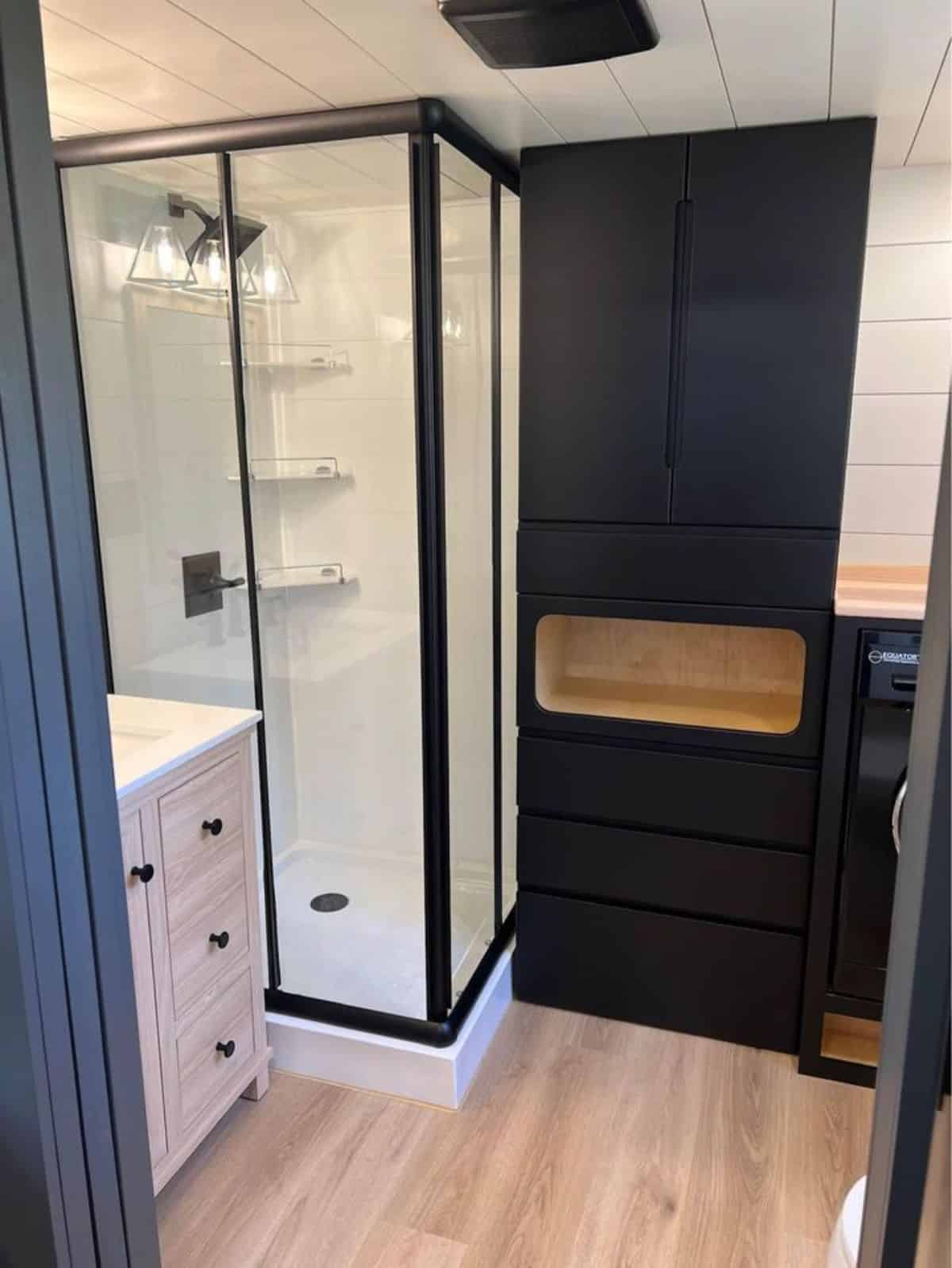 bathroom of beautiful tiny home has standard fittings with full length shower area with glass enclosure