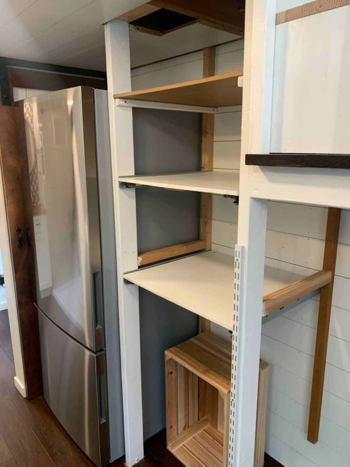 storage racks underneath the stairs and huge double door refrigerator in the kitchen