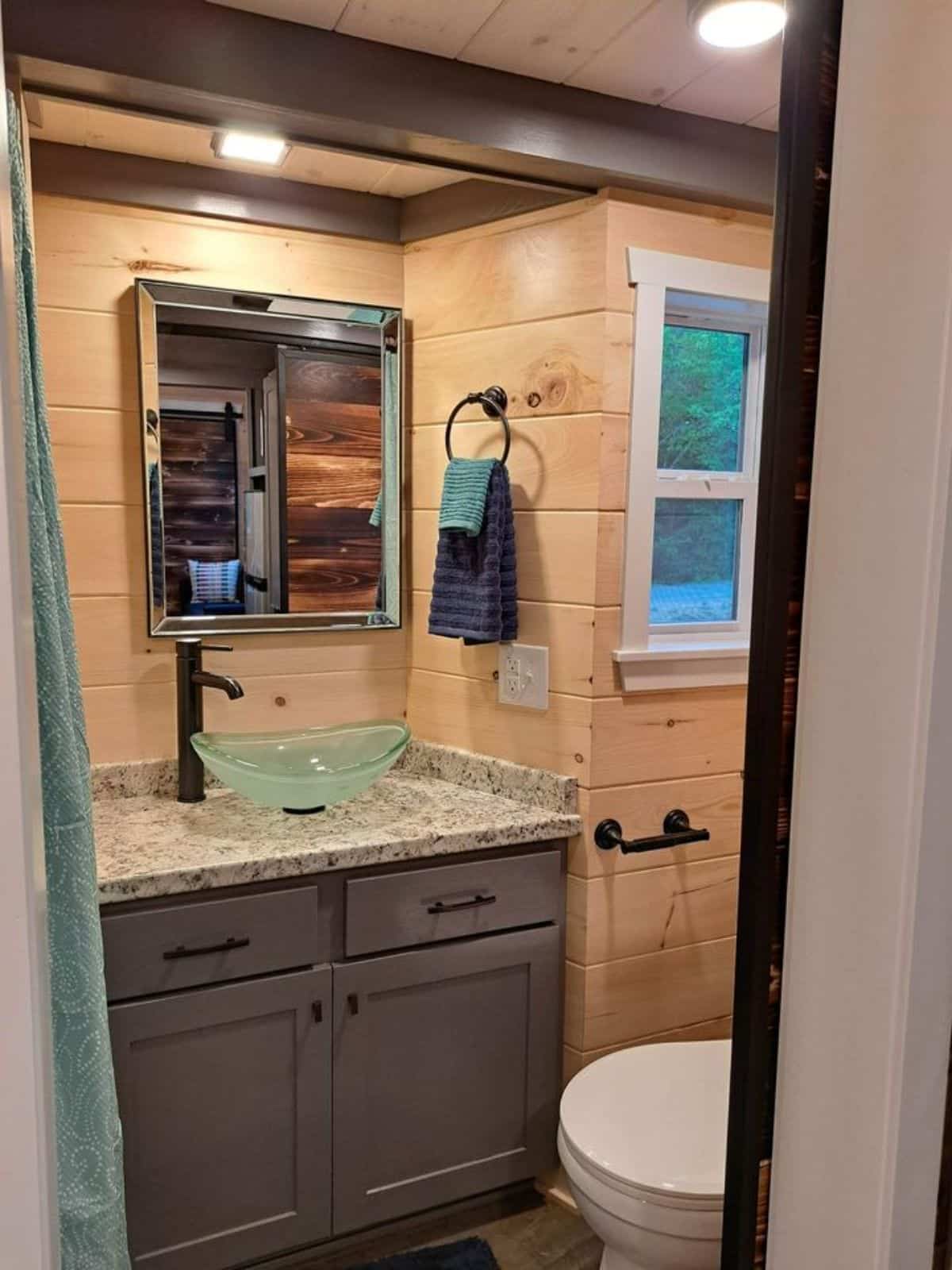 standard toilet, sink with vanity and mirror in bathroom of 30’ tiny house on wheels