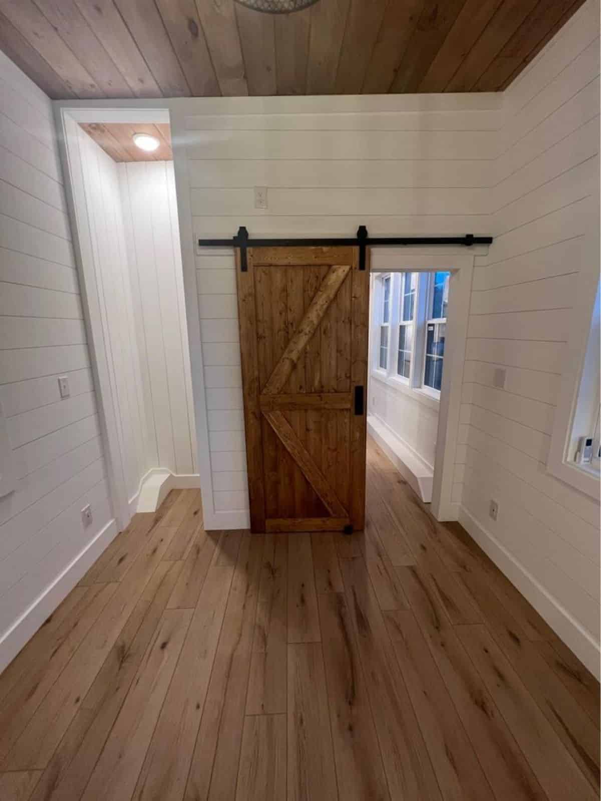 bedroom of brand new 36’ tiny house has a small wardrobe behind the sliding door