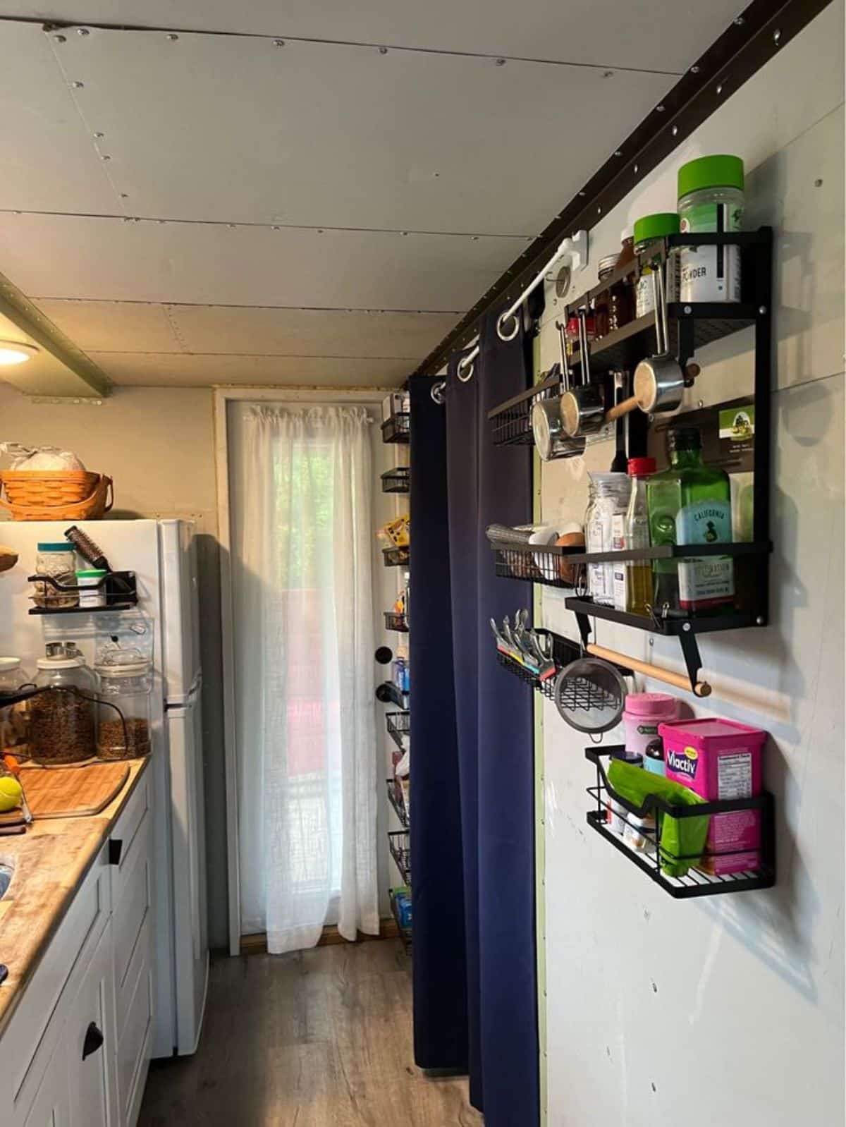 shelves opposite to the kitchen countertop has all the kitchen items