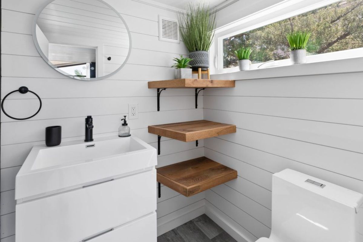 open shelves, standard toilet and sink with vanity in bathroom of gorgeous tiny house