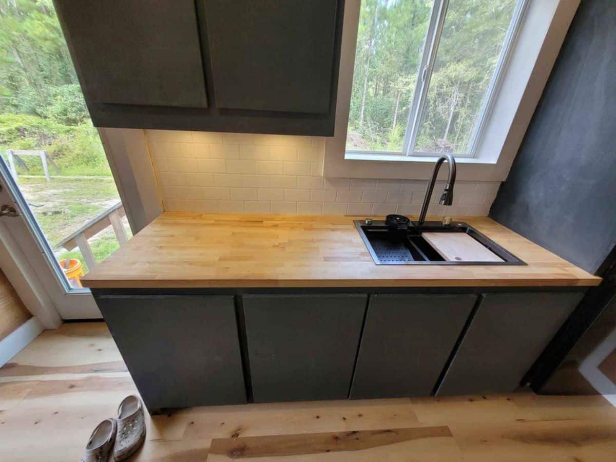 opposite side of the kitchen has open countertop with sink and storage