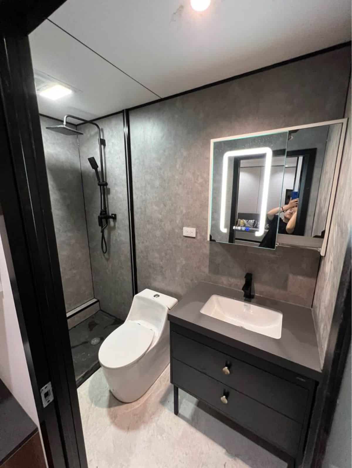 bathroom of tiny house with a slide is just stunning with standard toilet, sink with vanity and separate shower area