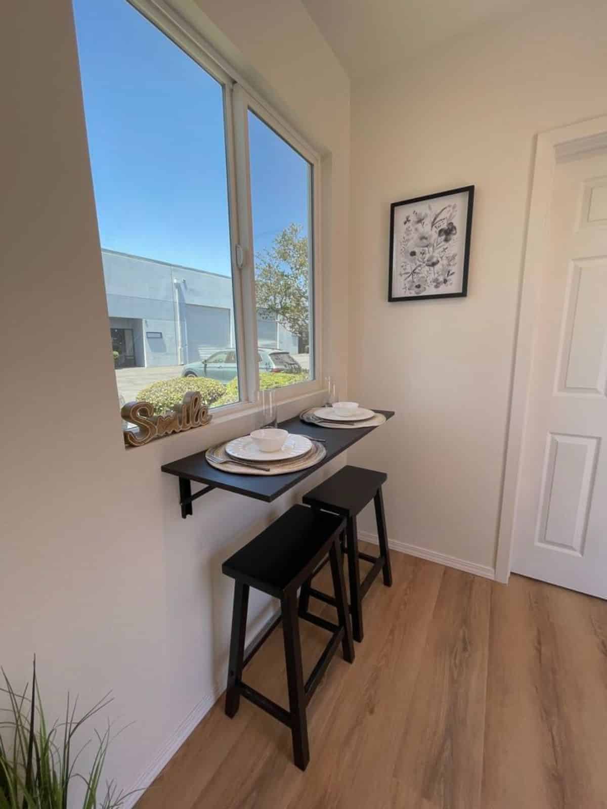 small dining table with 2 stools besides the window