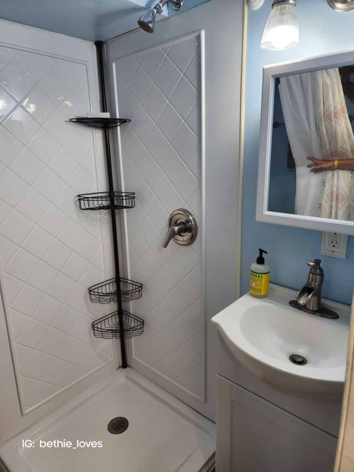 full length shower area and sink with vanity with mirror