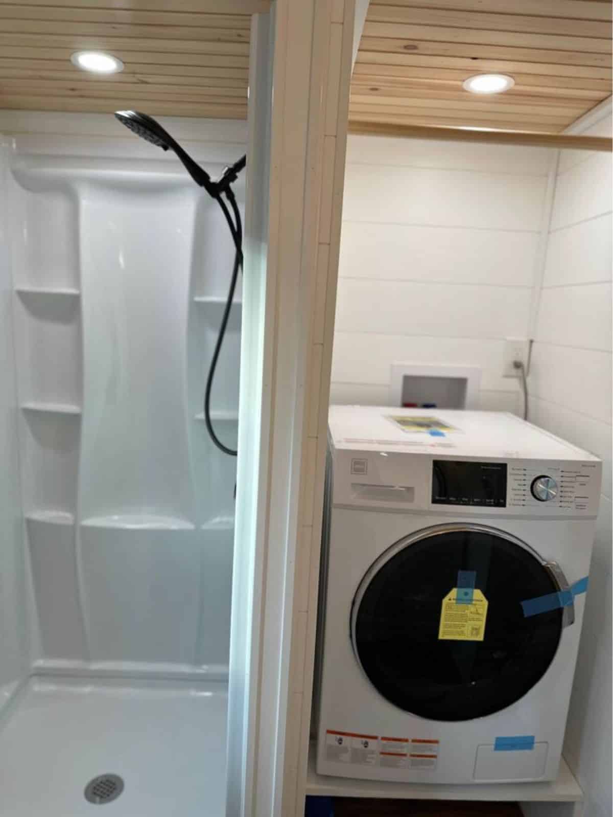 full length shower area with washer dryer in bathroom