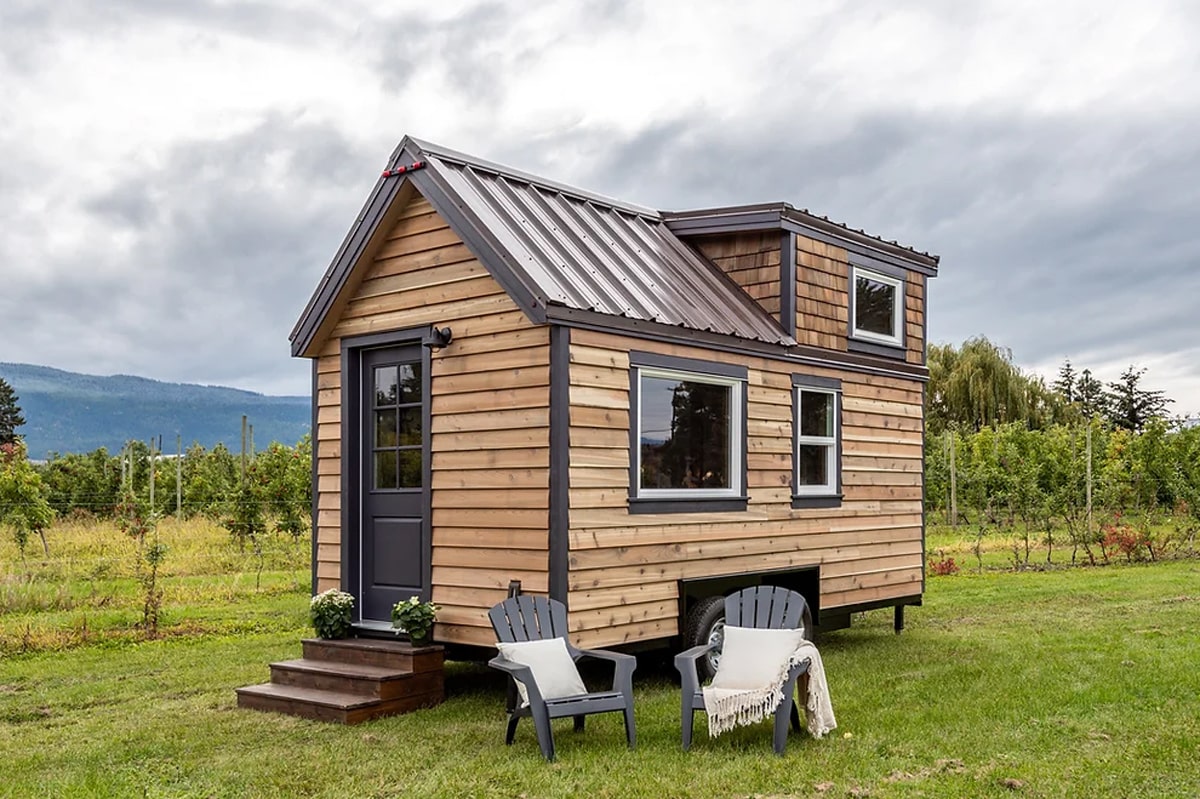 wooden tiny home and two black chairs