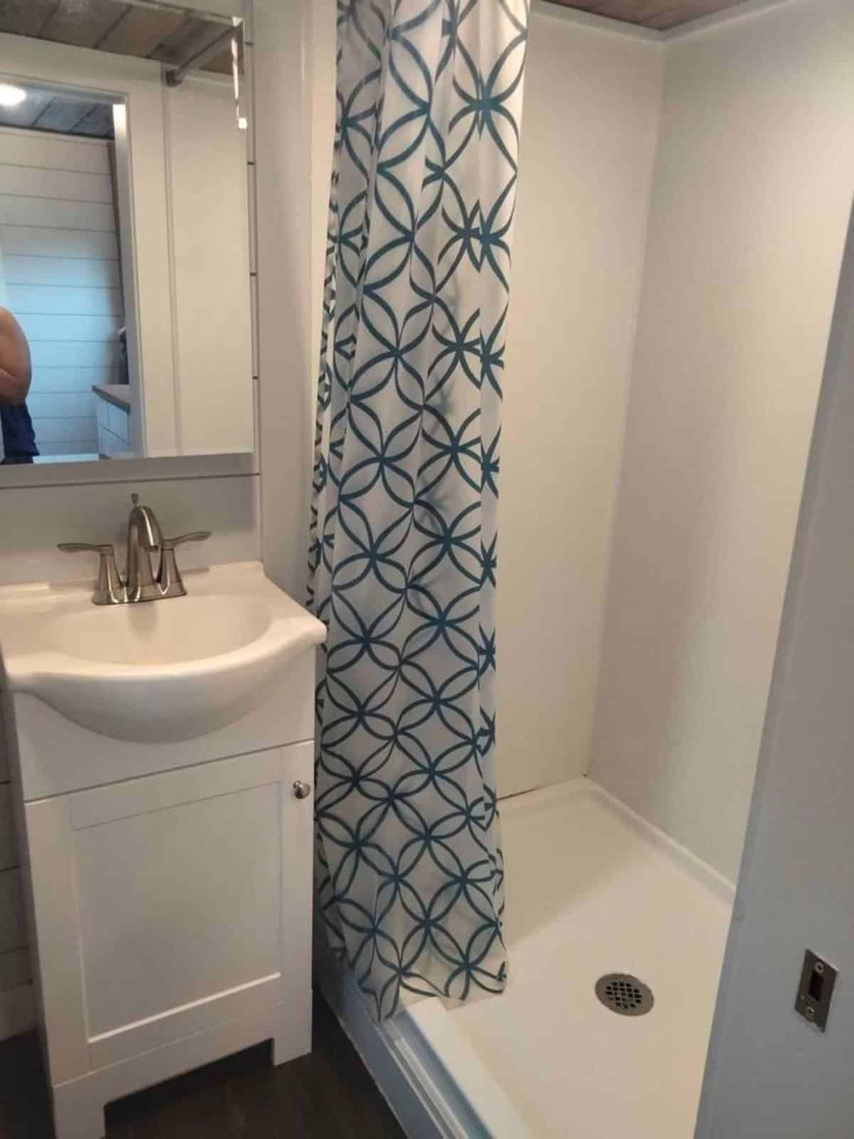 full length shower area with sink and vanity of three bedroom tiny home