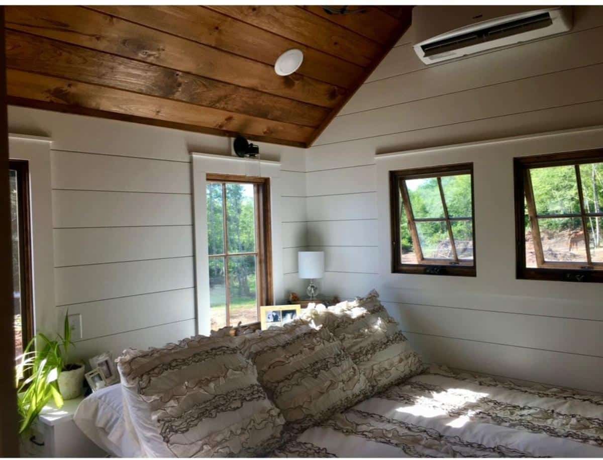main floor bedroom is very comfortable  with multiple windows of 3 bedroom tiny home
